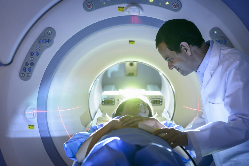 Doctor leaning over MRI patient with encouragement. | Netherlands oncology
