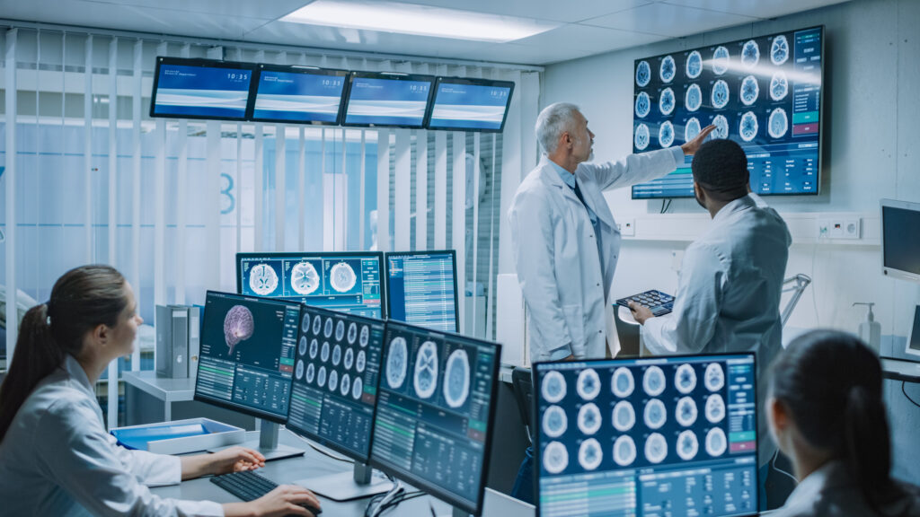 Team of Professional Medical Scientists Work in the Brain Research Laboratory. Neurologists / Neuroscientists Surrounded by Monitors Showing CT, MRI Scans Having Discussion and Working on Personal Computers. | Invest in Holland