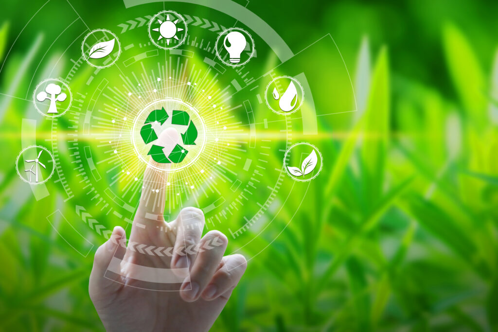 A hand pointing to a green recycling image in the middle surrounded by white icons in a circular formation pertaining to wind turbines, trees, leaves, the sun, a lightbulb and a water droplet in front of a green grass background | Invest in Holland