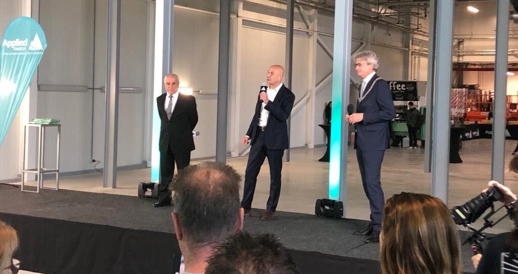 Three men in suits speaking on stage at the opening of the new Applied Medical sterilization facility in Amersfoort.