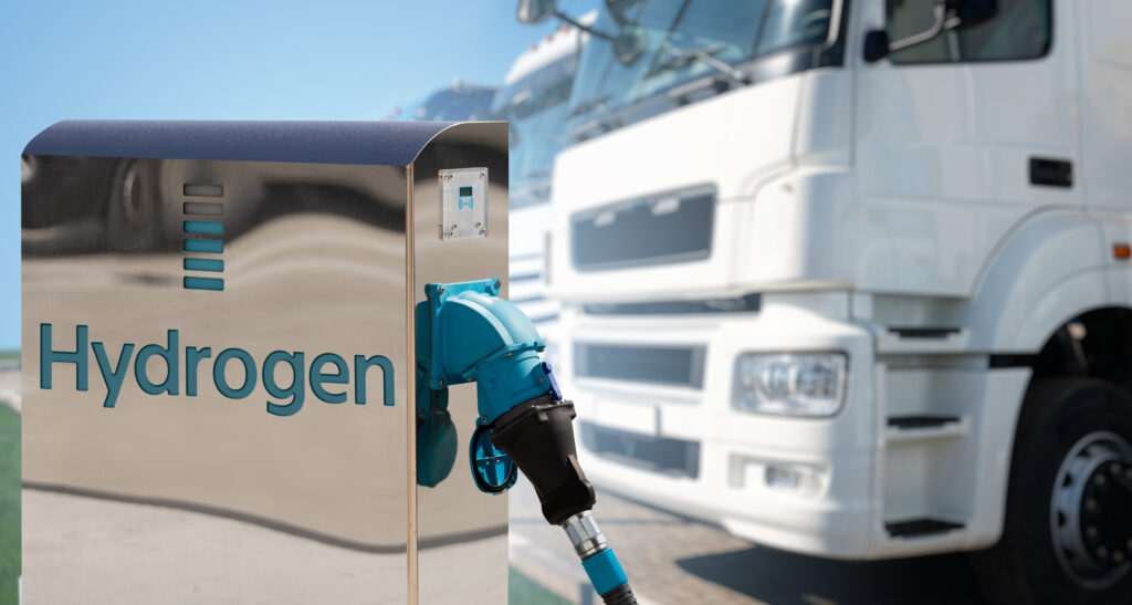 Hydrogen energy pump with a row of transport trucks in the background.