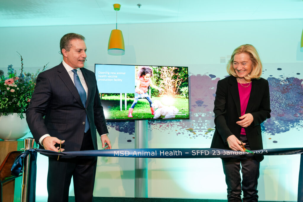 Man in dark suit with blue tie and woman in dark suit with pink shirt cut ceremonial ribbon