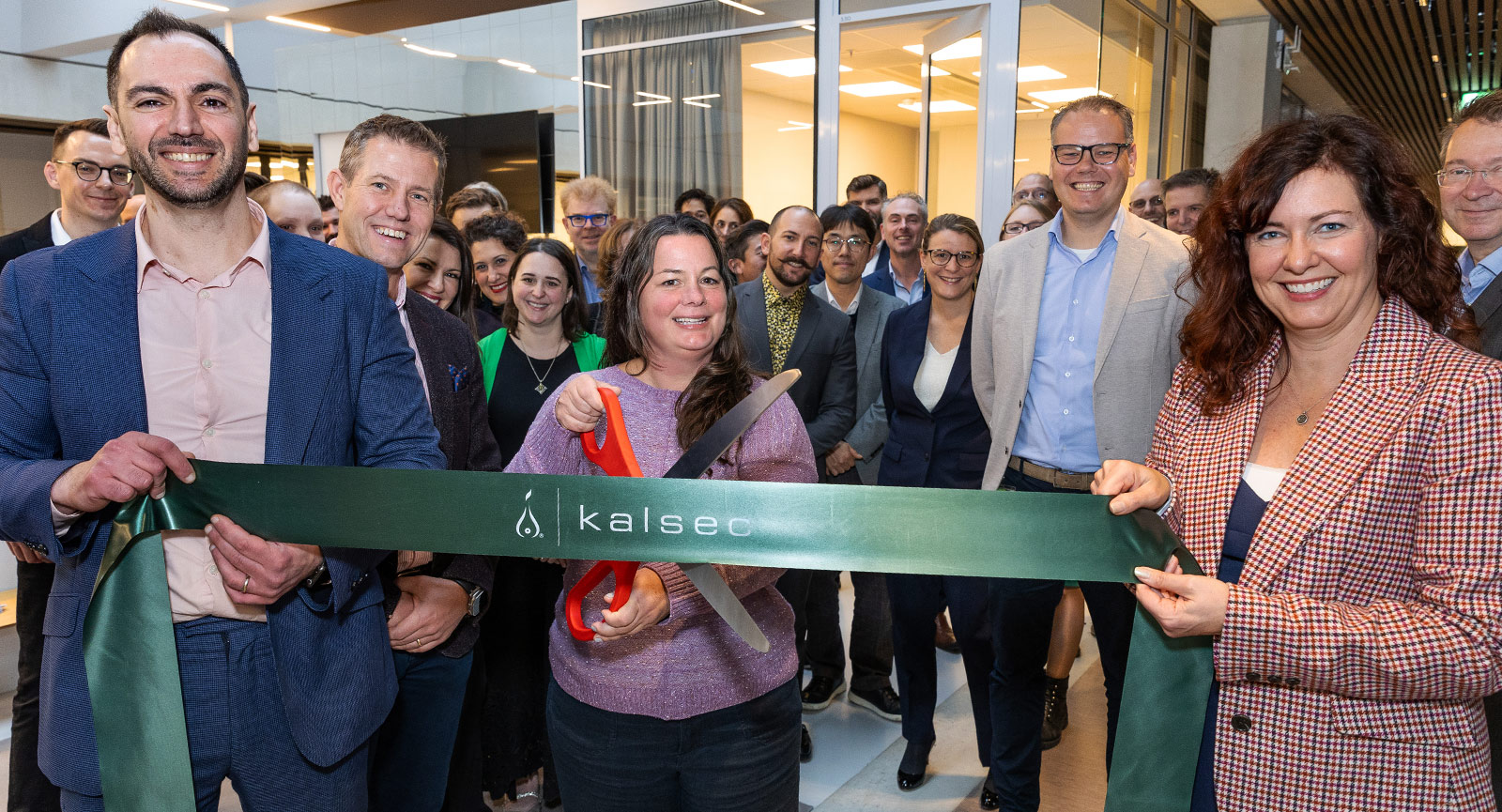 A group of people facing the camera hold a green ribbon that reads, "Kalsec" — Invest in Holland.
