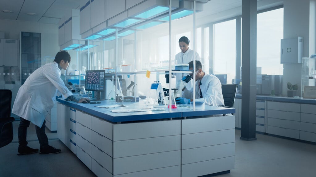 Medical Science Laboratory with Diverse Team of Biochemistry Scientists Developing Drugs, Medicine, Doing Biotechnology Research. Working on Computer, Using Microscope, Analysing Samples.