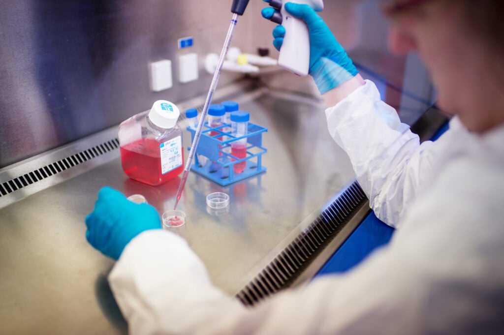 Person in lab coat using a dropper