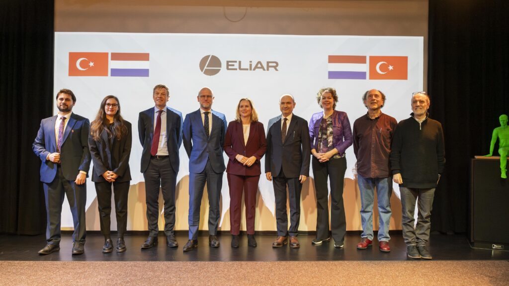 ELiAR Featured Image: Dutch Foreign Trade Minister Reinette Klever, Chair of VNO-NCW Ingrid Thijssen, Ambassador of the Netherlands Joep Wijnands and ELiAR’s team posing in front of a projection of the ELiAR company logo and the Netherlands and Türkiye flags. Invest in Holland.
